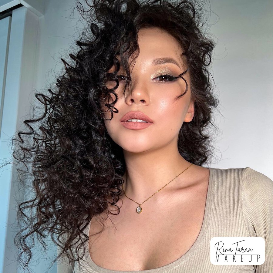 Winged liner and a gold lid on natural dark curls, skin left glowing