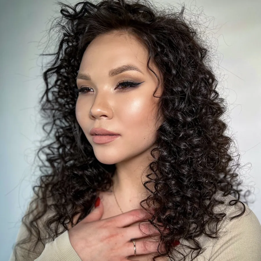 Soft bronze eye with a fine liner on curly hair, dewy skin finish