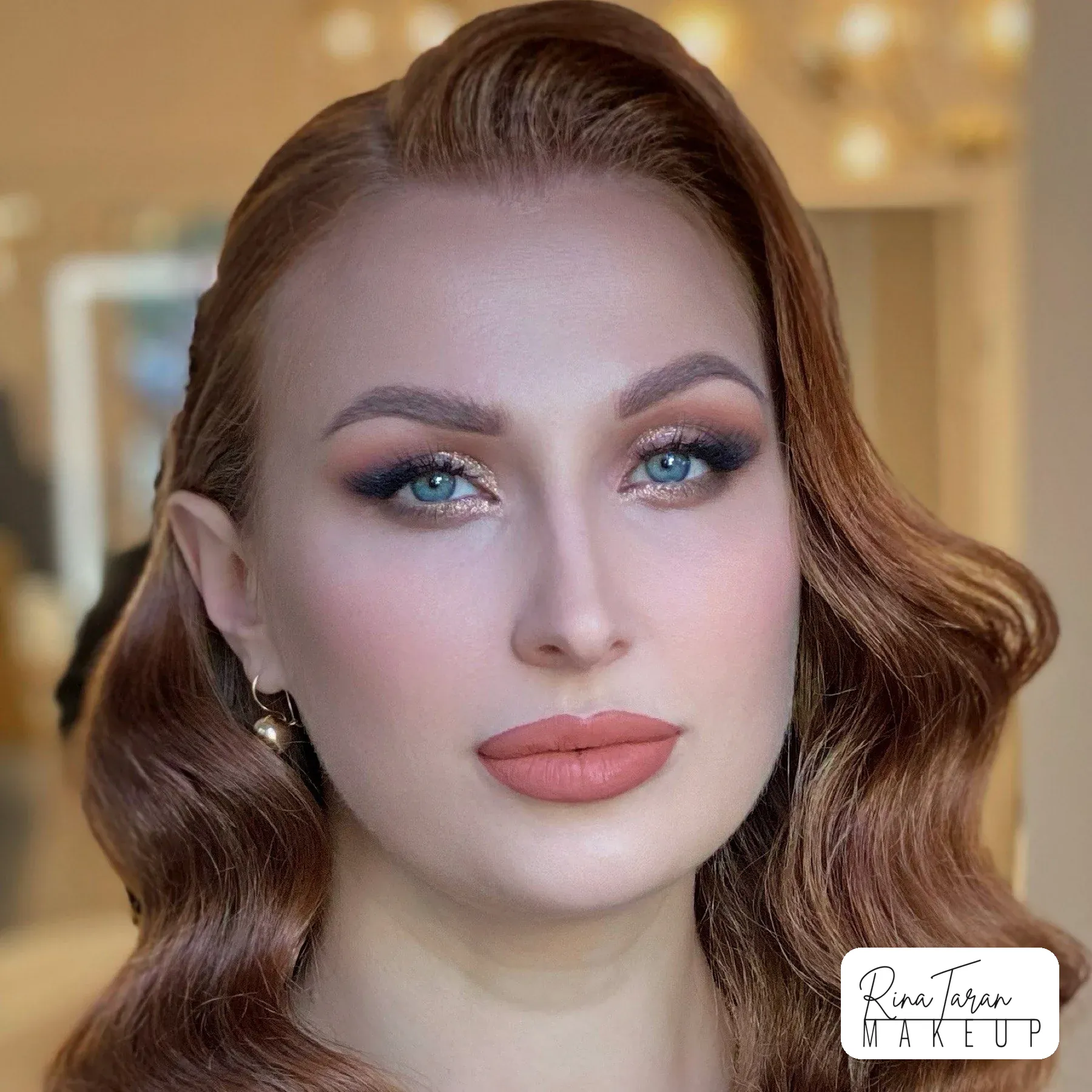 Teal smoky eye and a warm coral lip on red hair, makeup built for a long day