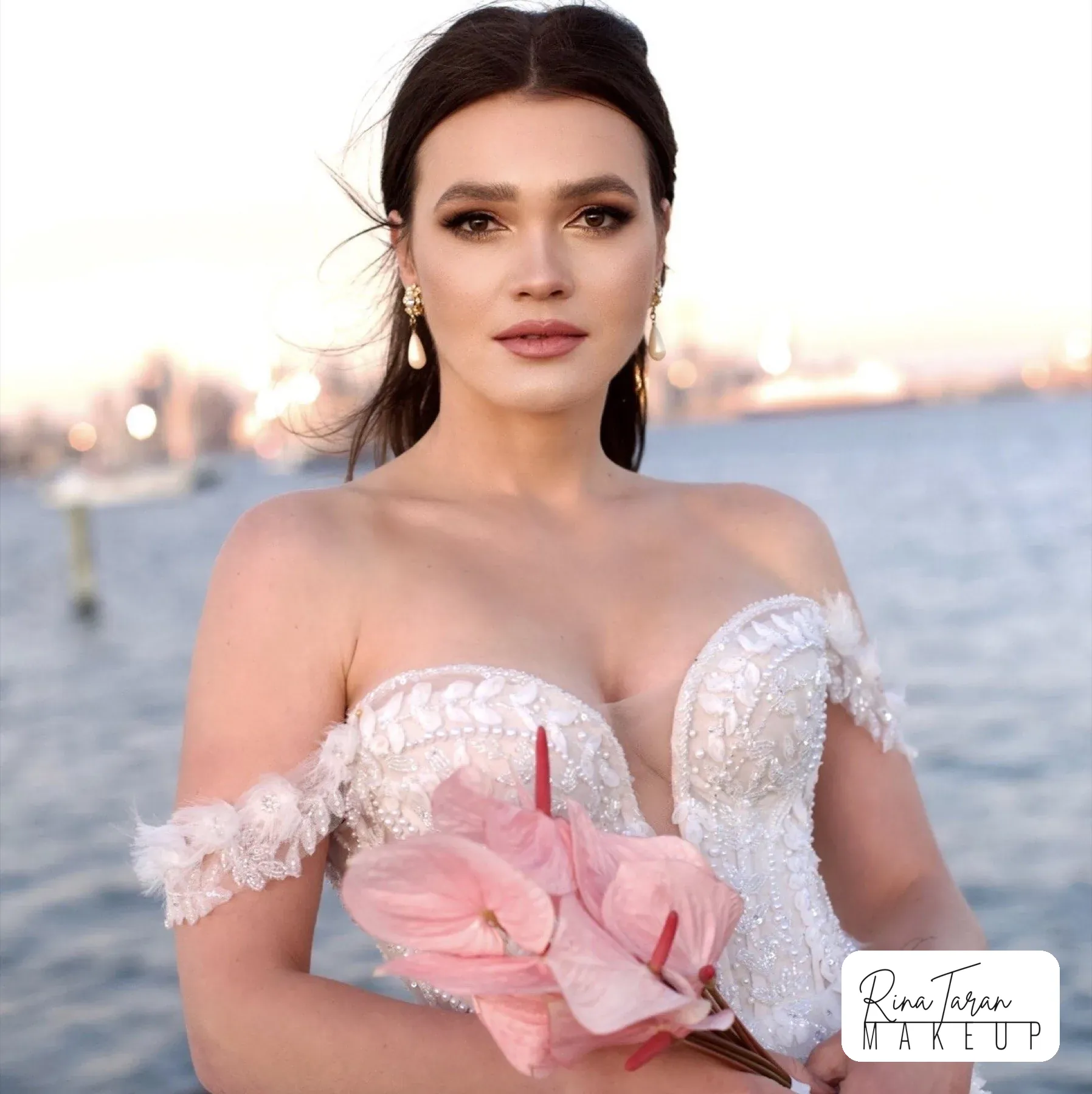 Bronze smoky eye and a dark low updo on a bride photographed beside open water
