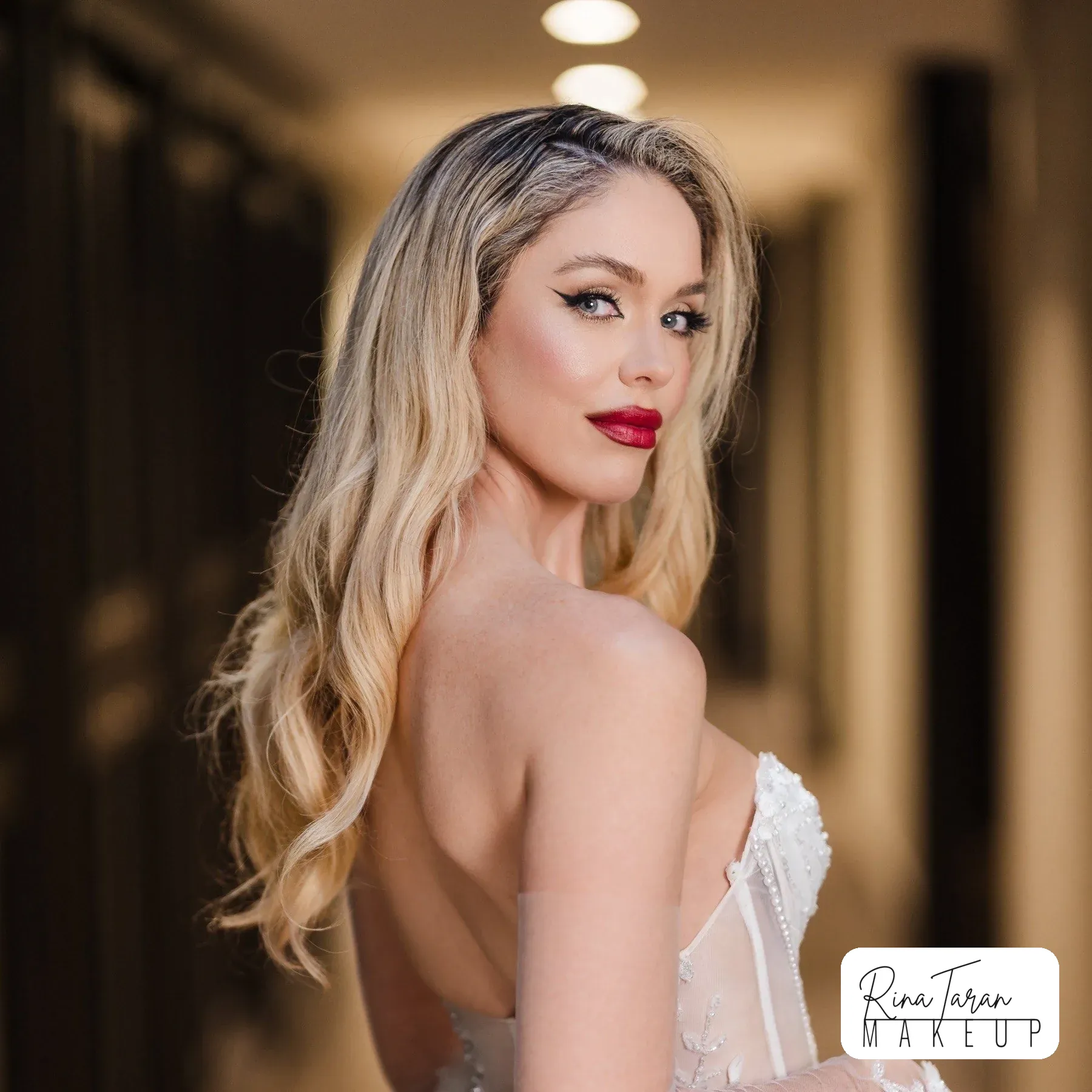 Red lip and bronzed skin on long blonde hair, over the shoulder