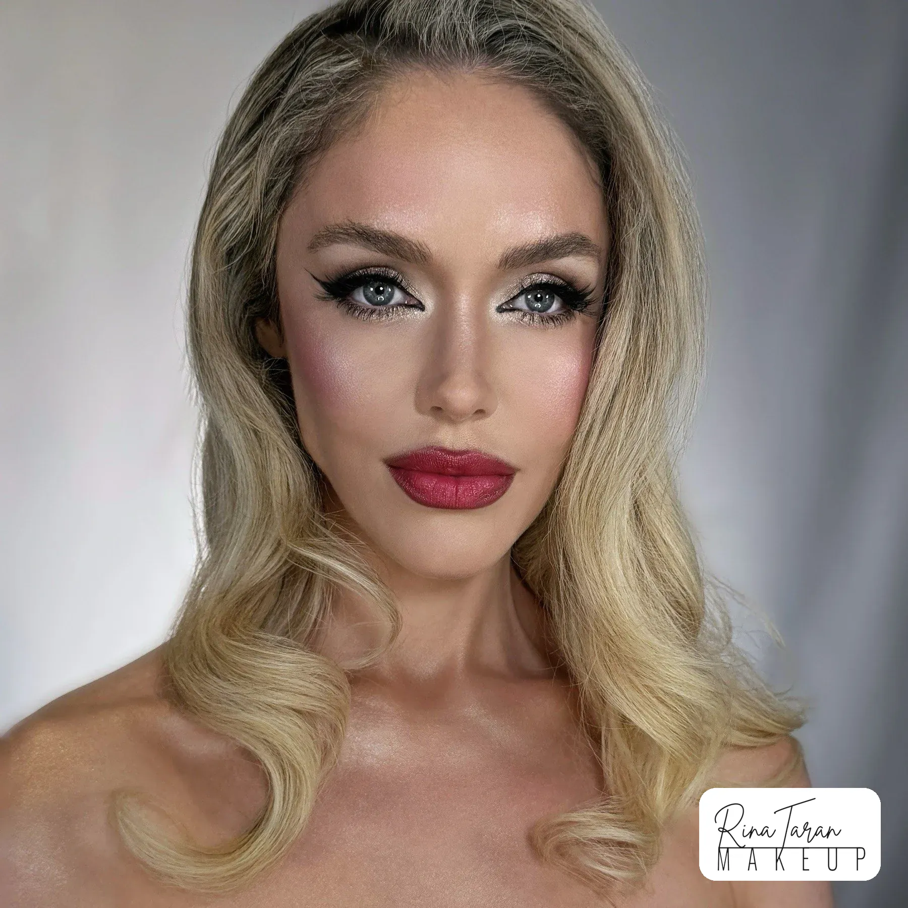 Deep red lip with a graphic black wing, in Hollywood waves