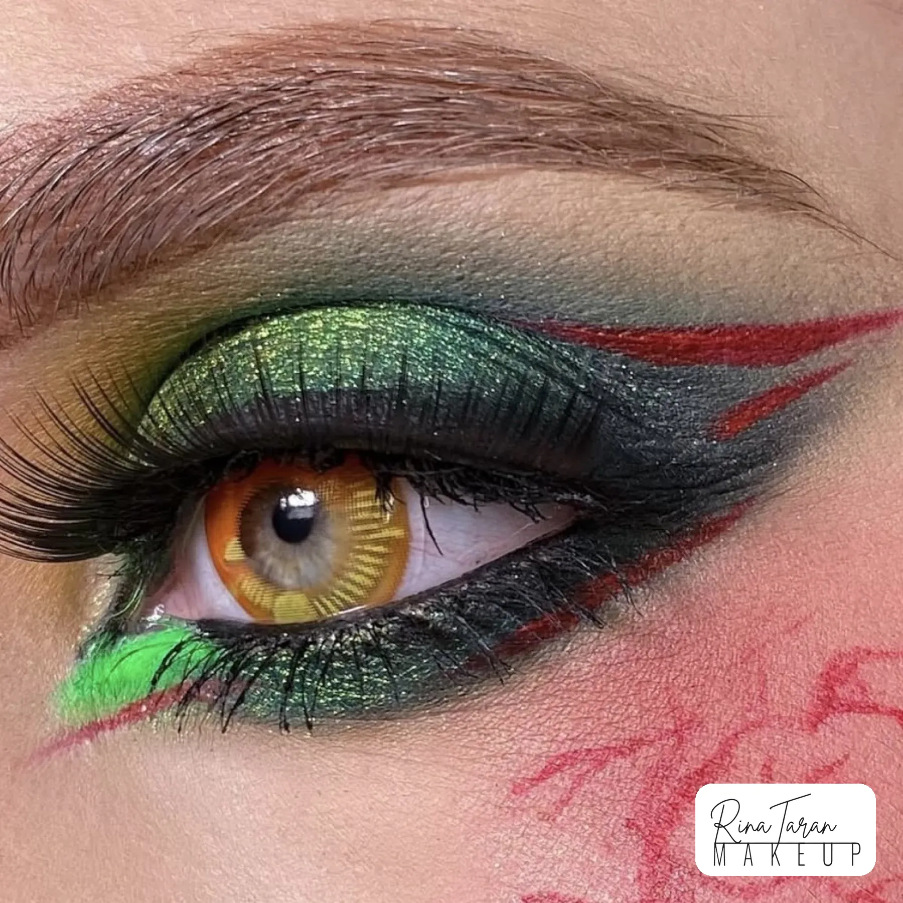 Avant garde eye makeup: green metallic lid with red graphic lines and an orange lens