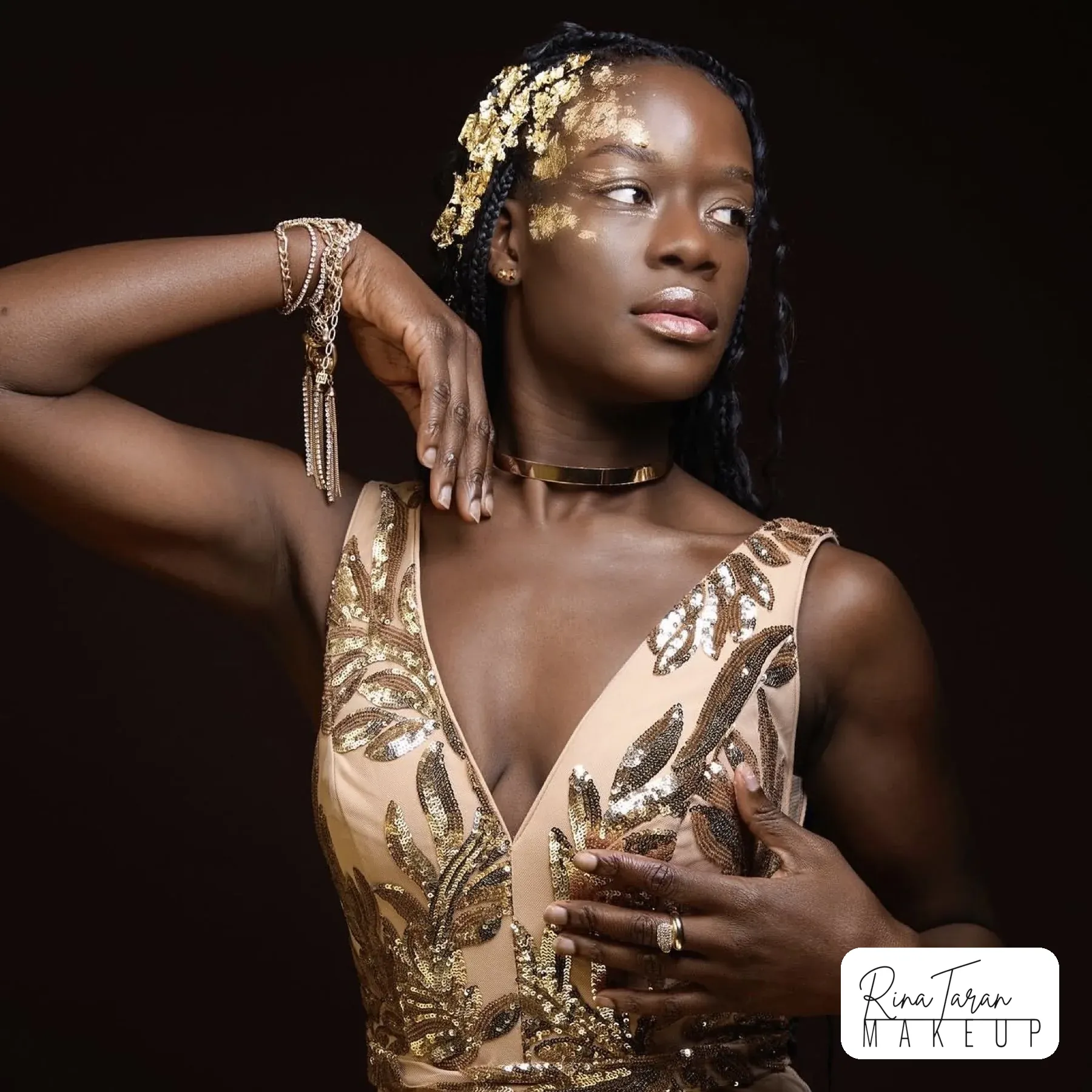 Studio editorial on deep skin tone with gold leaf at the temple and glossy skin