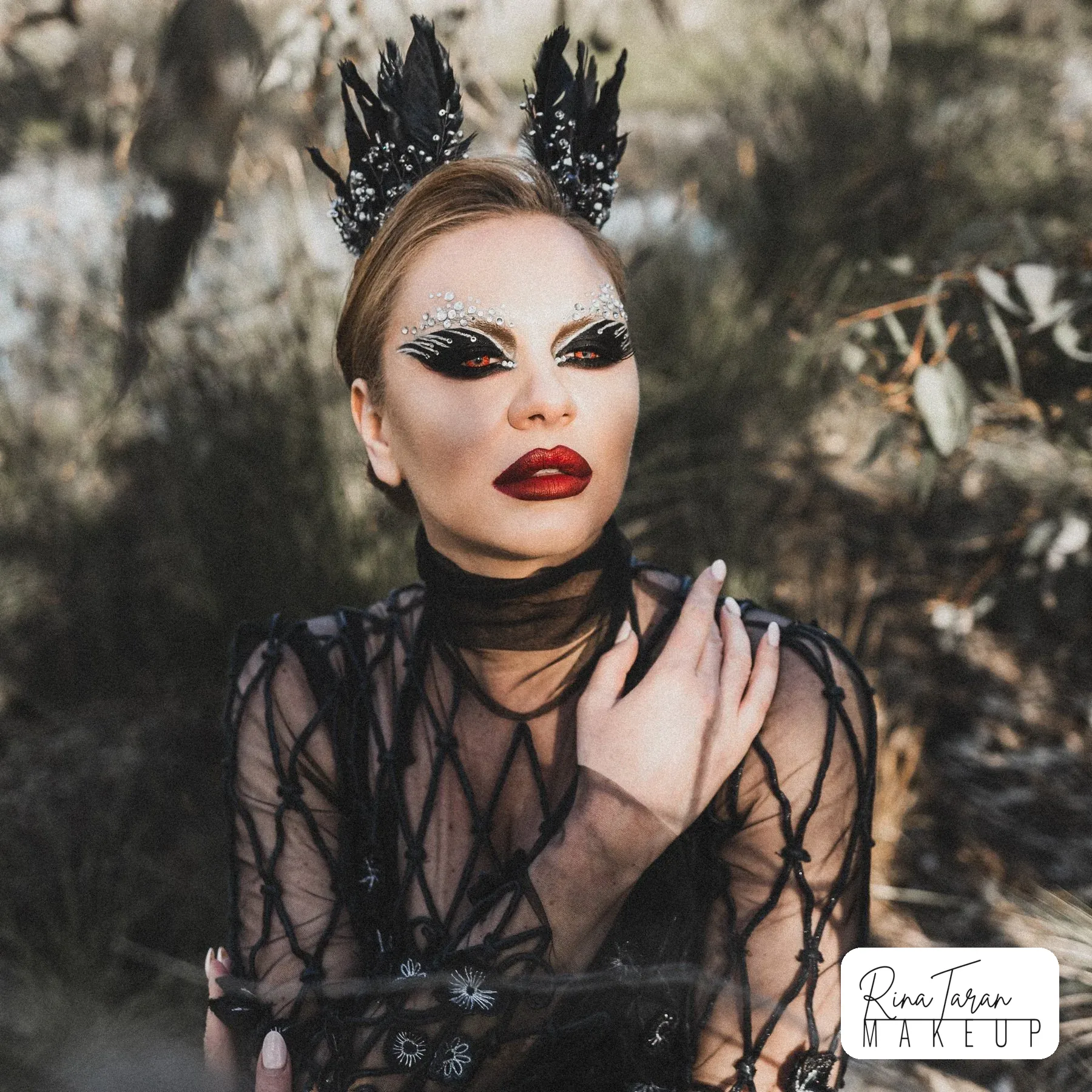 Character makeup for a dark swan concept: black feathers, pearls on the lid and a red lip