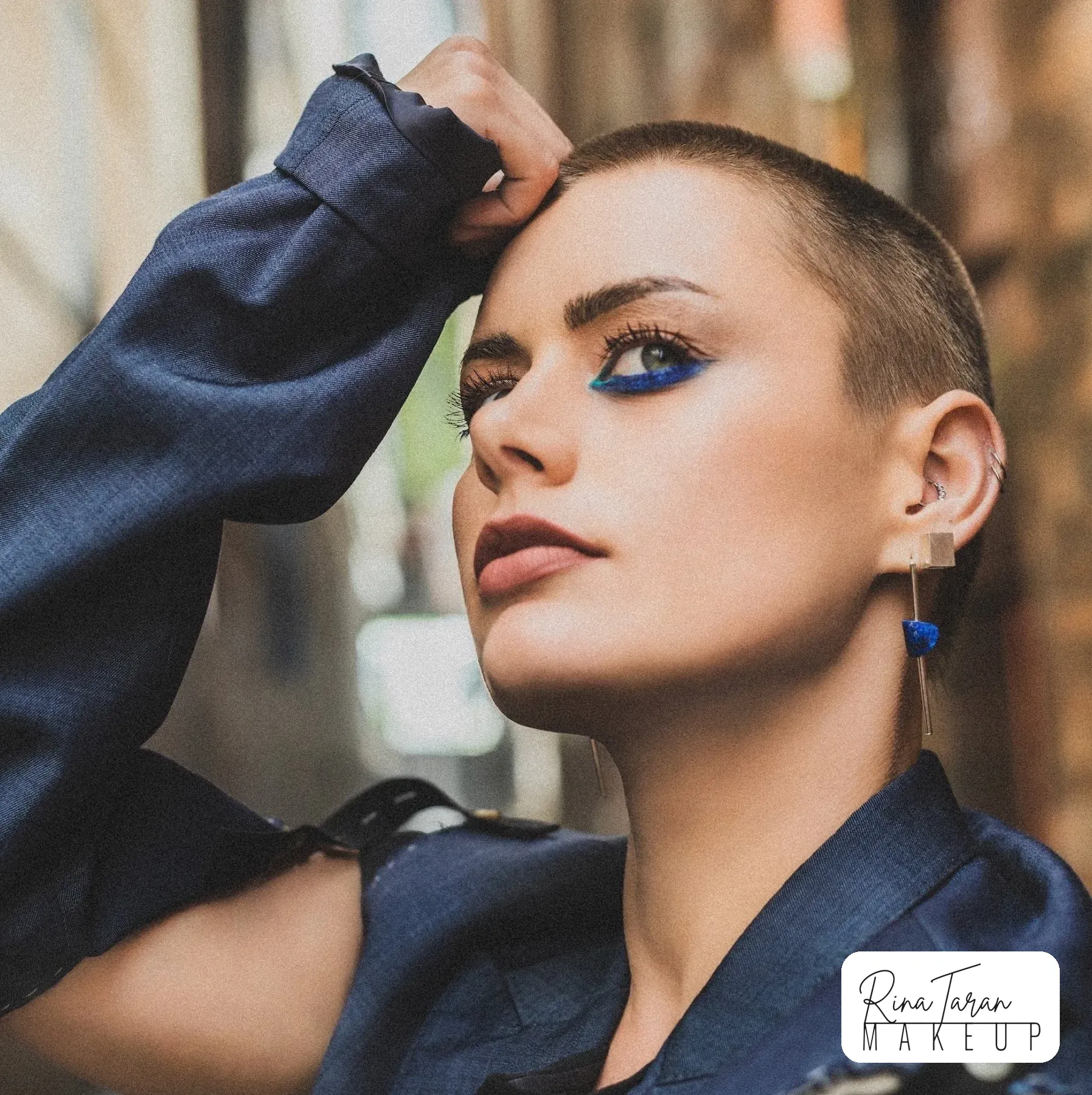 Editorial portrait with electric blue graphic liner on a shaved head