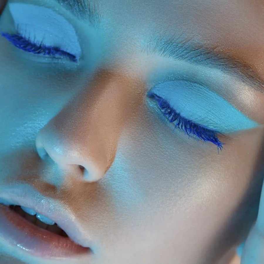 Editorial and creative makeup with painted blue lids and cobalt blue lashes