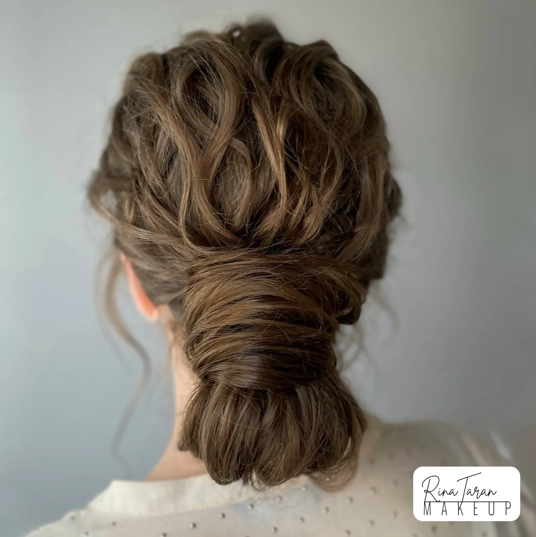 Undone low chignon with a twisted crown, wedding hair styled to survive a whole day