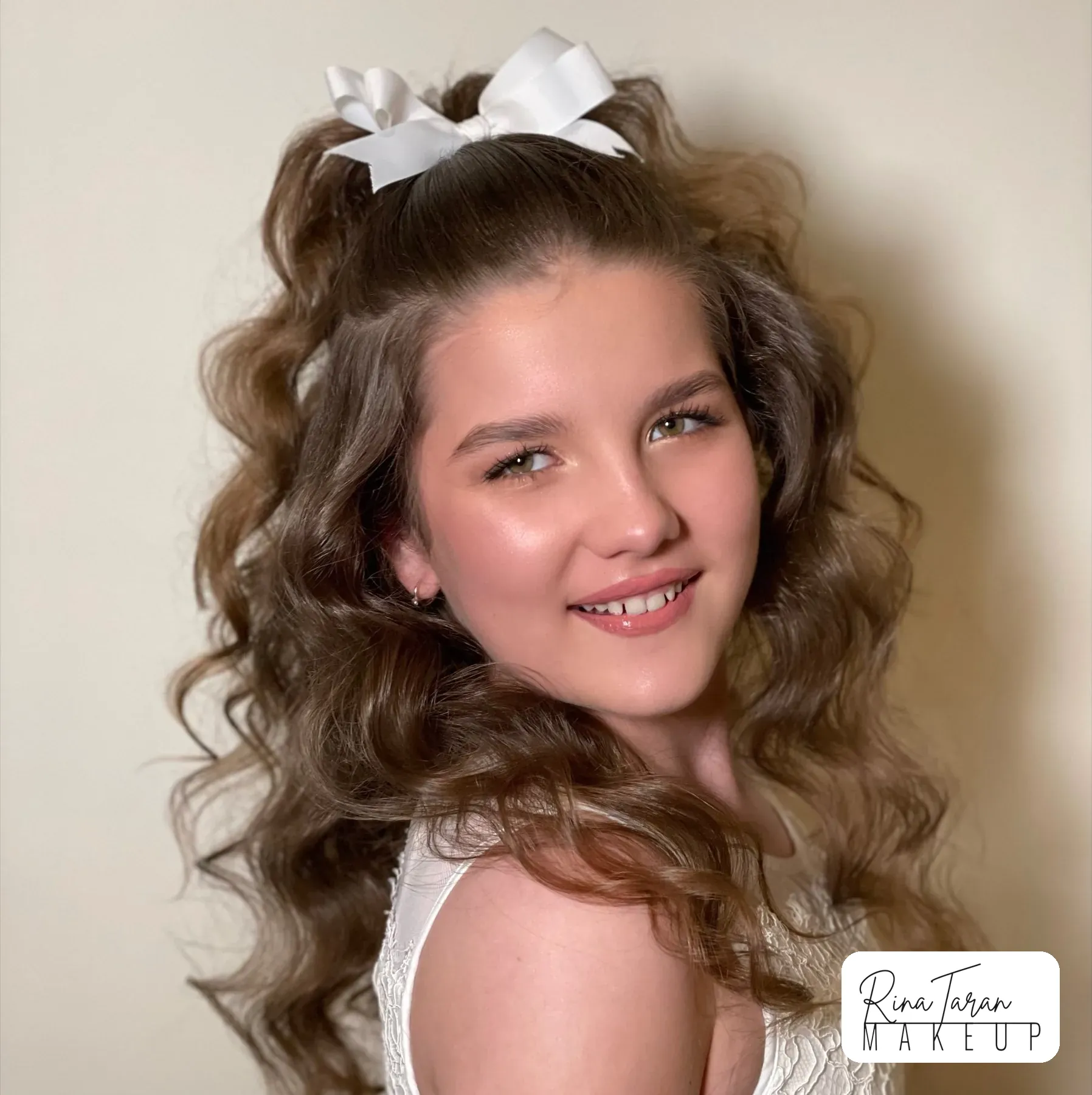 Half up half down curls with a white bow, a first hair styling for a young girl