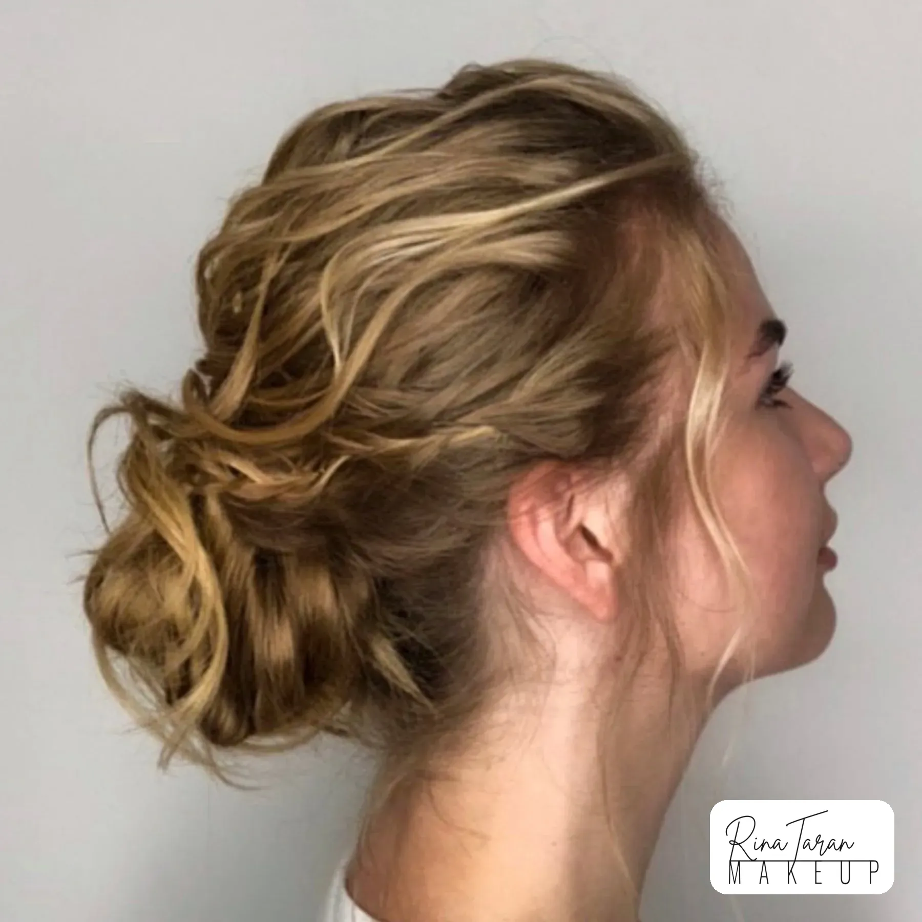 Undone updo with soft height at the crown for a wedding guest, with soft natural makeup to match