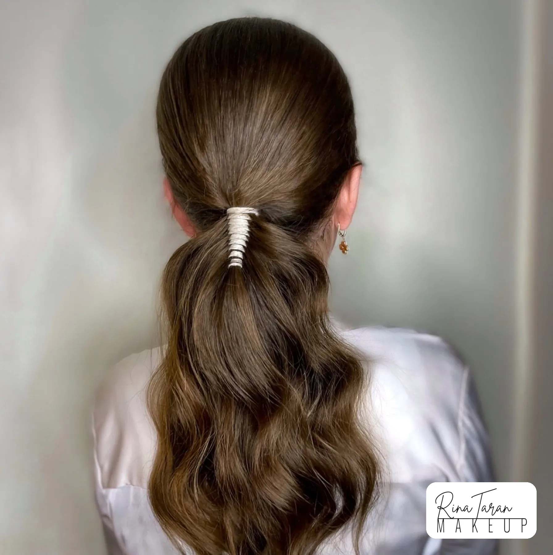 Low ponytail with a hair cuff and a softly waved length, everyday event styling