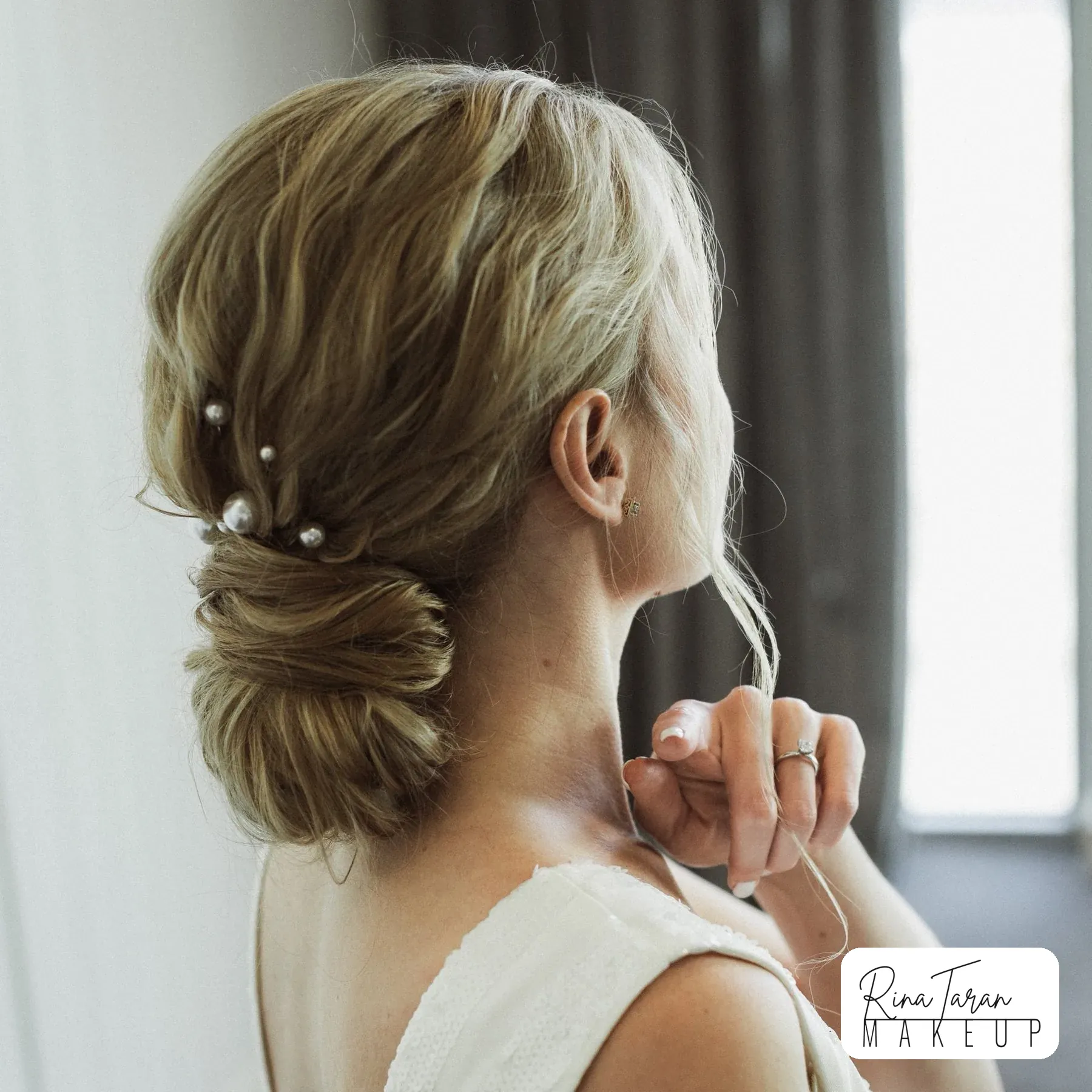 Low twisted chignon on blonde hair, pinned with pearls for an evening in town