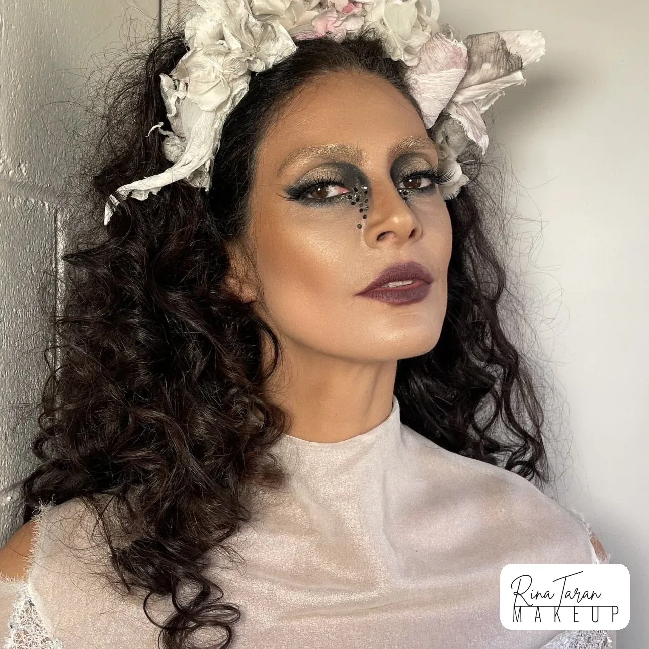 Defined curls with a floral headpiece for an editorial shoot, with a dark graphic eye and a deep plum lip