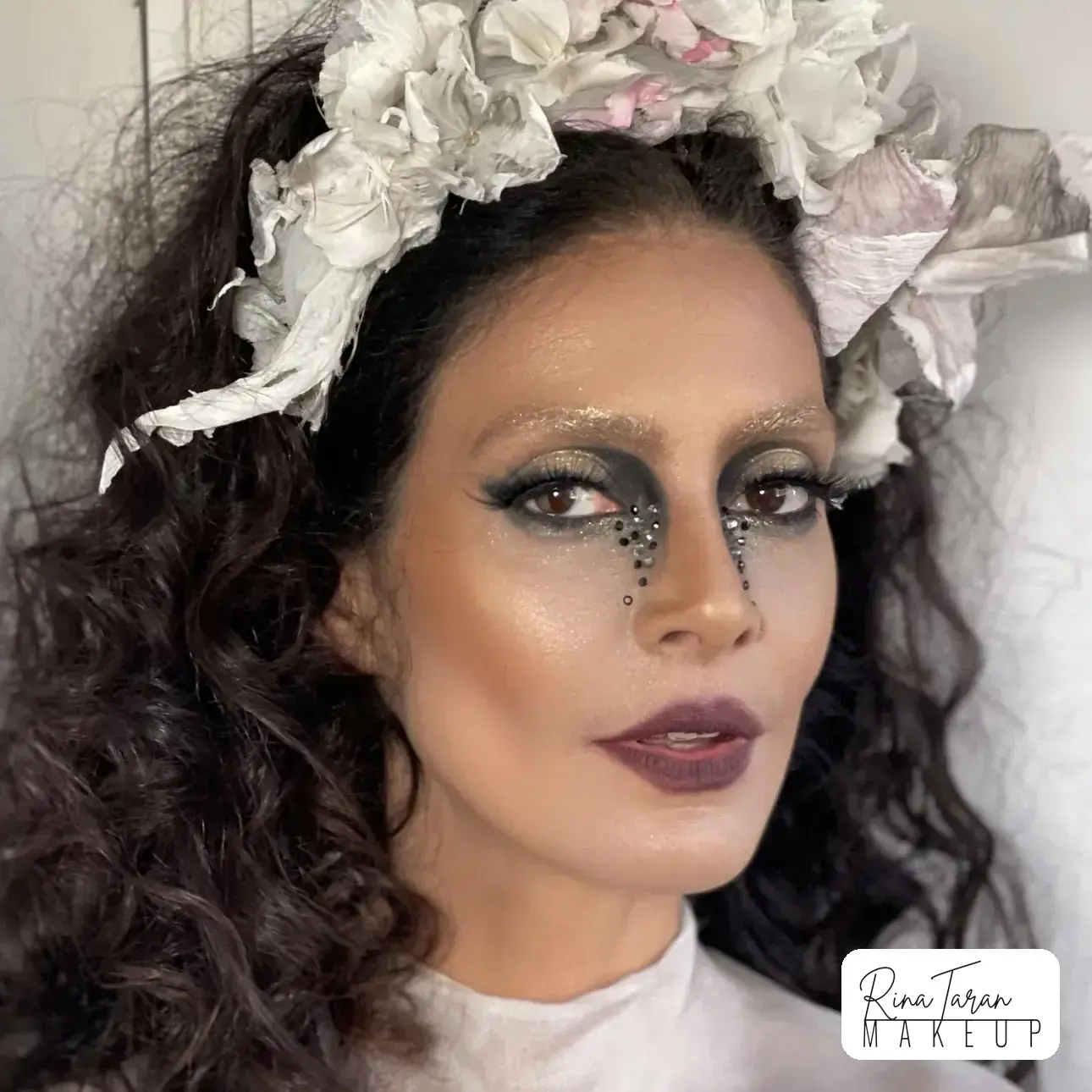Dark fairy makeup look with a smoked charcoal eye and silver glitter running down the cheek
