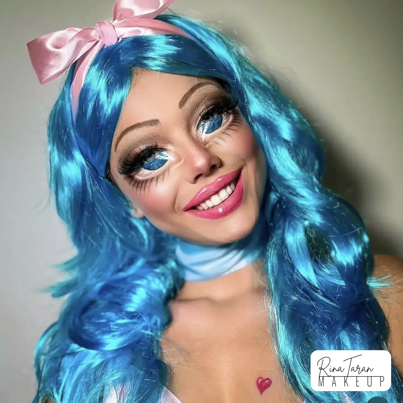 Doll makeup look with eyes painted twice their size, high round blush and a pink bow lip