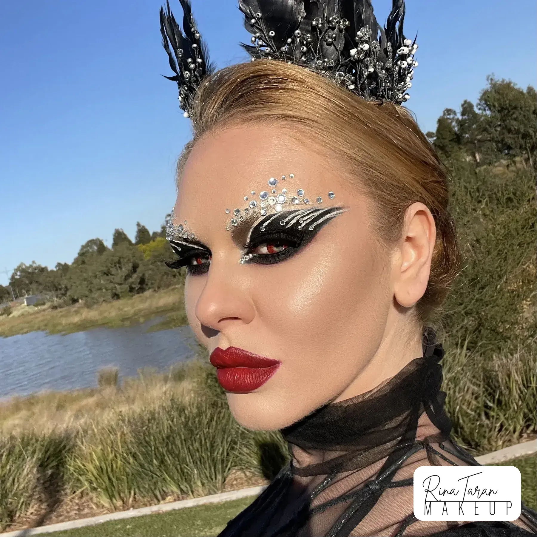A crystal wing drawn out over the lid, worn with a black crown and a deep red lip