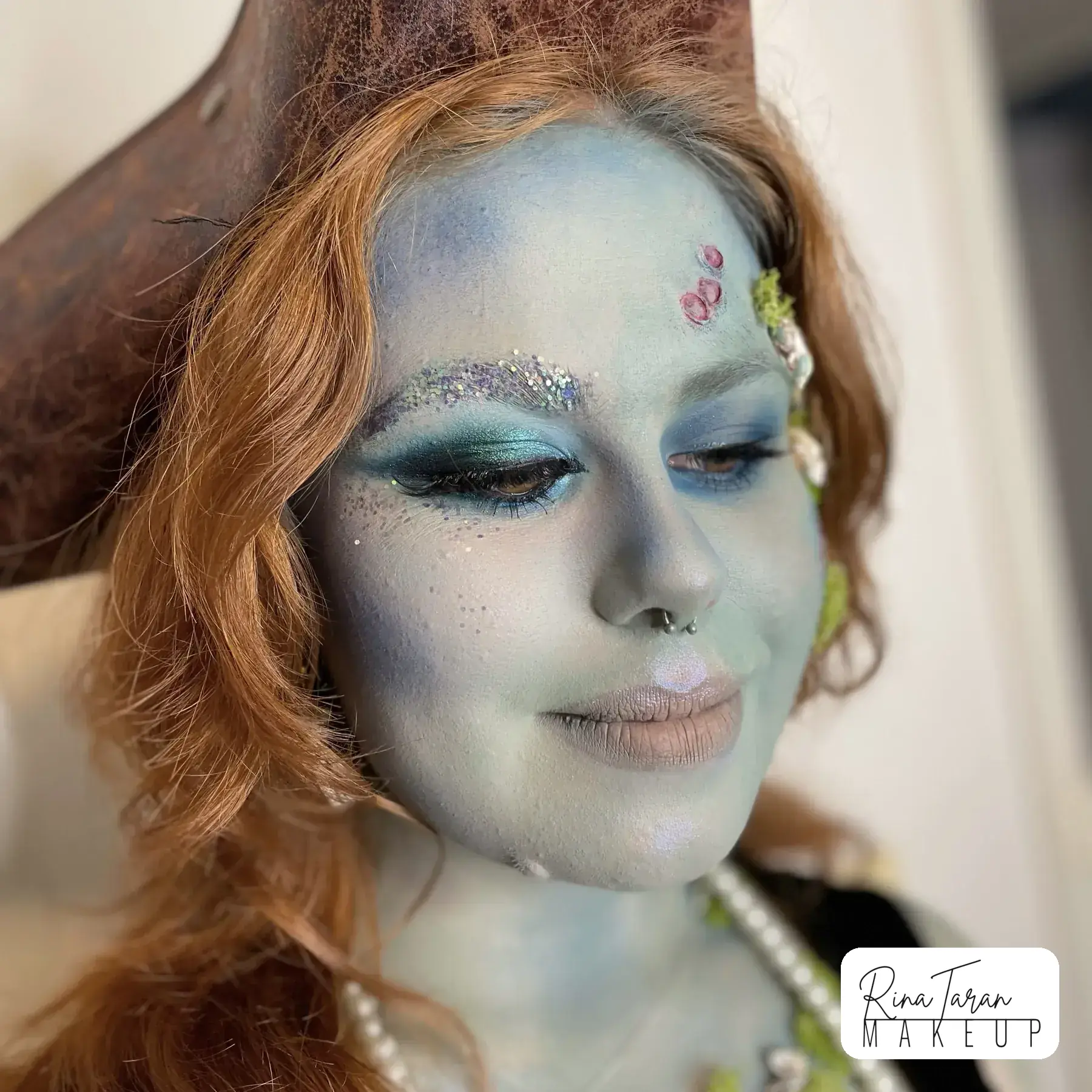Drowned sailor makeup look with blue green skin, painted scales and a soft pearl eye