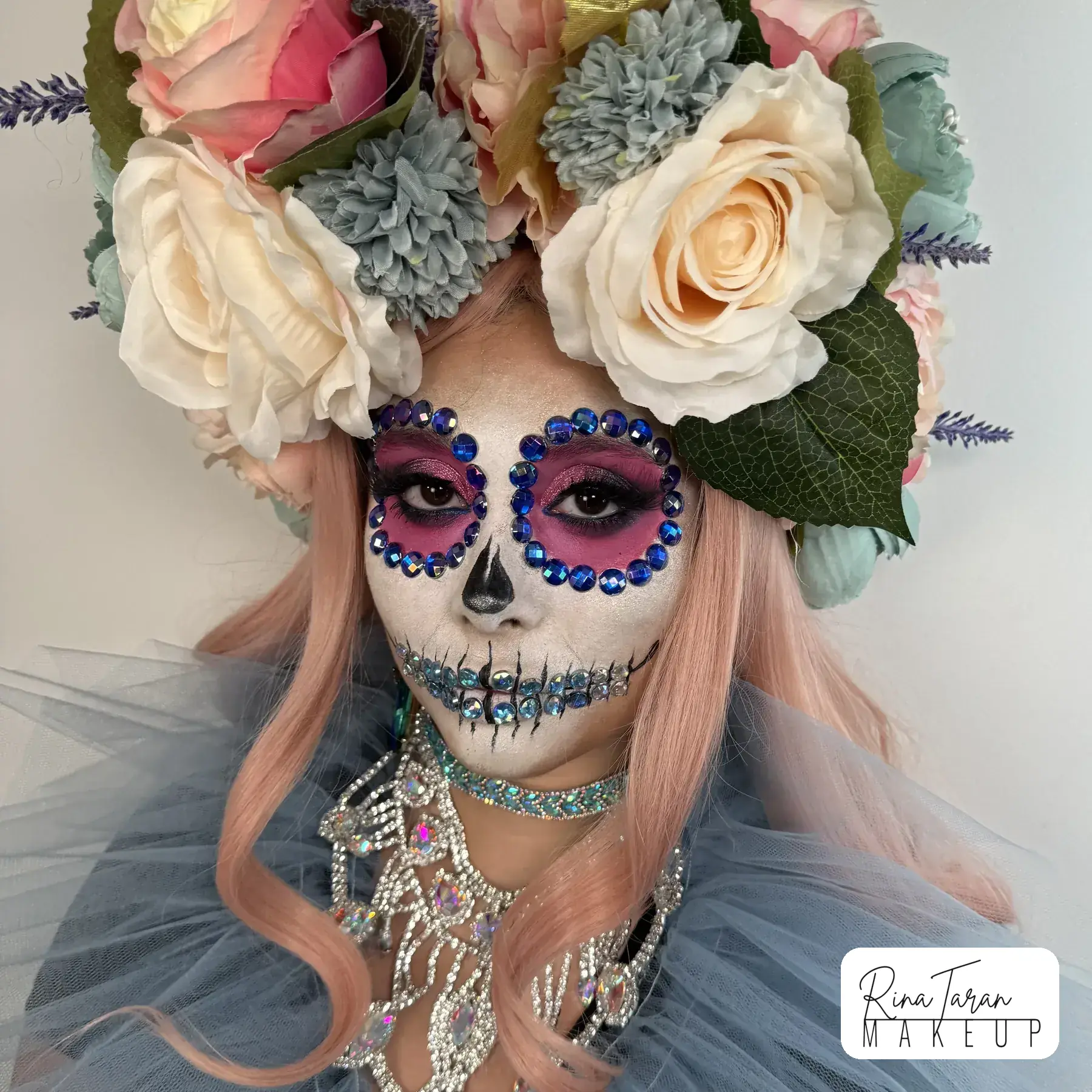 Santa Muerte makeup painted in colour and set with crystals, worn under a flower crown