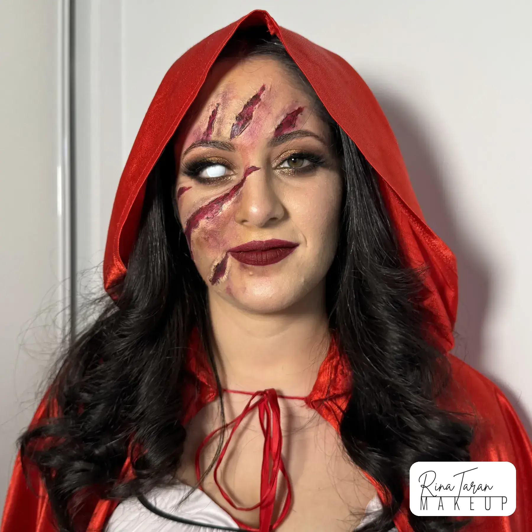 Little Red Riding Hood makeup with Halloween scars painted across the cheek and blood worked into the hairline
