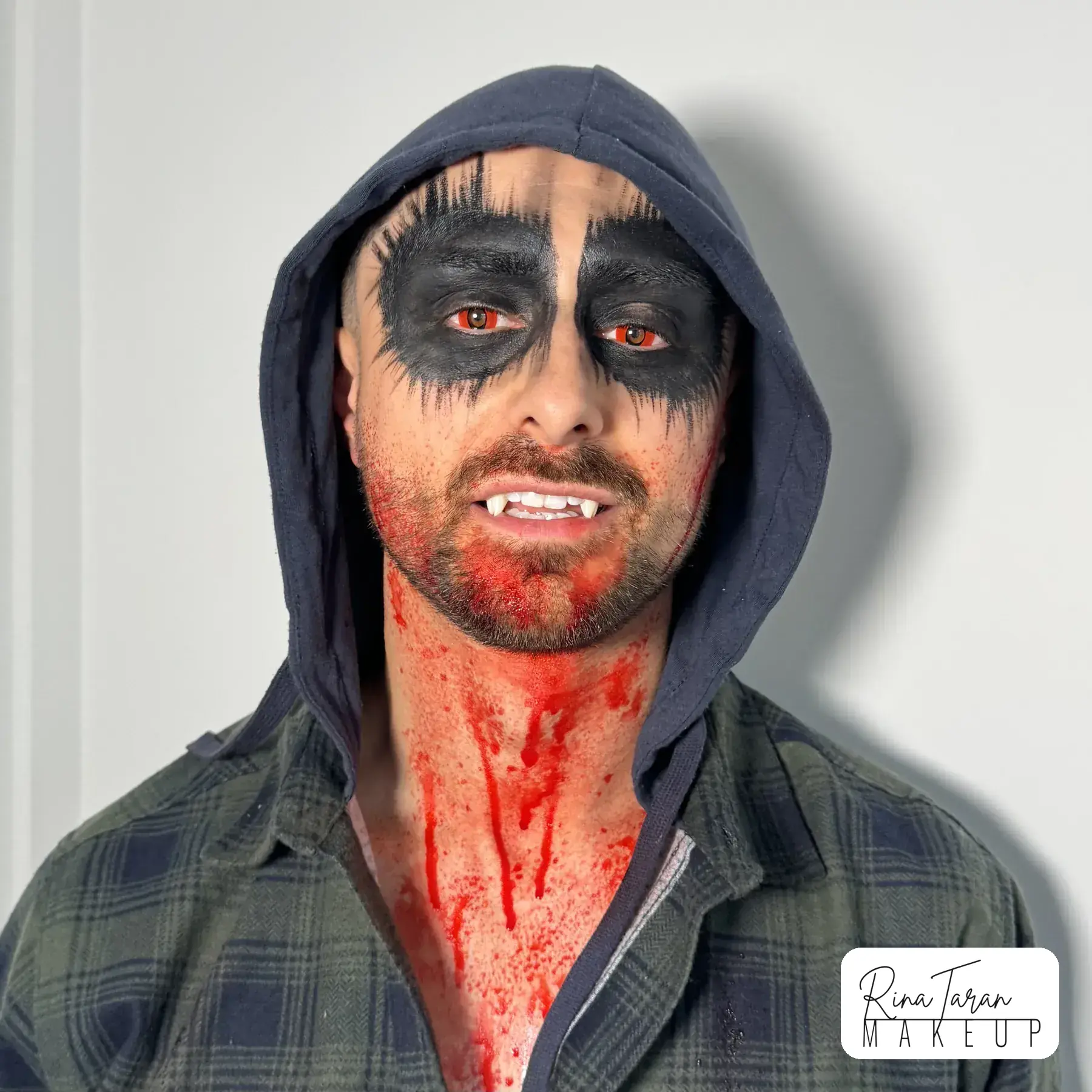Werewolf makeup on a man, a blacked out eye socket with blood run down the neck