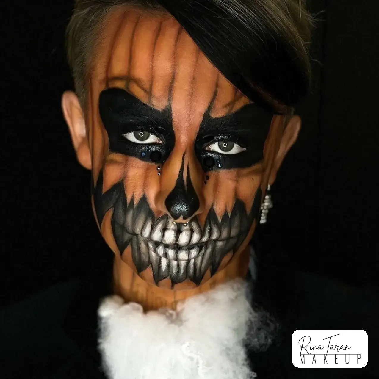 Jack o'lantern makeup painted across the whole face, with blacked out eyes and a full row of teeth