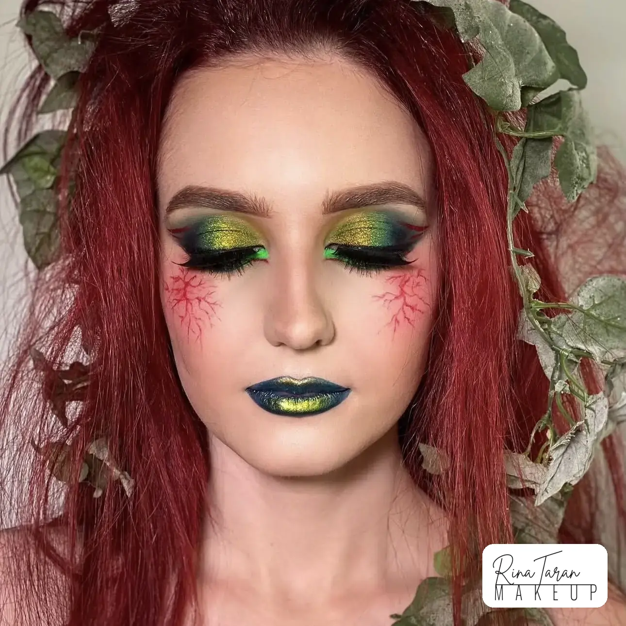 Green holographic shadow with red veins painted under the eye and a blue green lip
