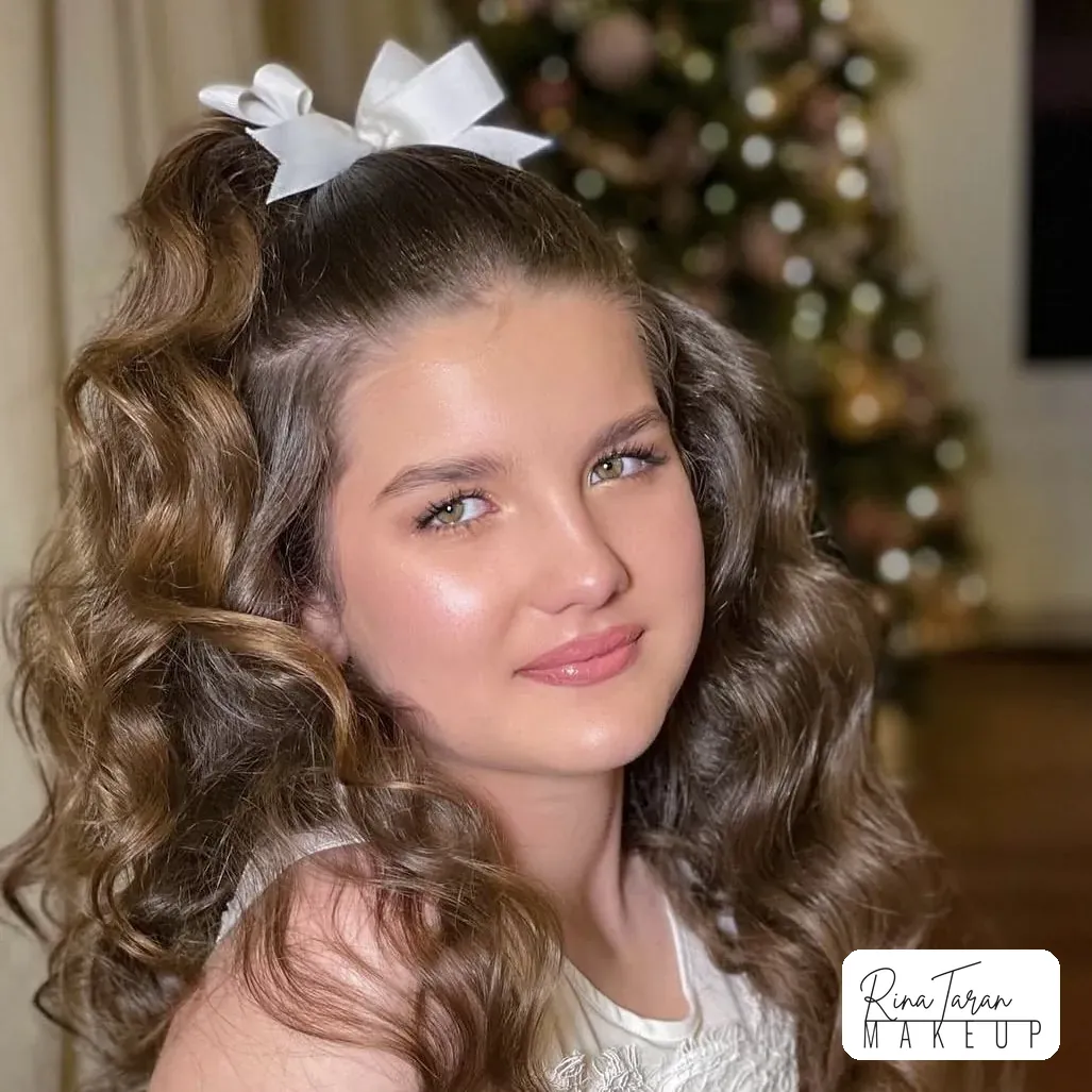 Soft party makeup and curls on a girl with a white bow