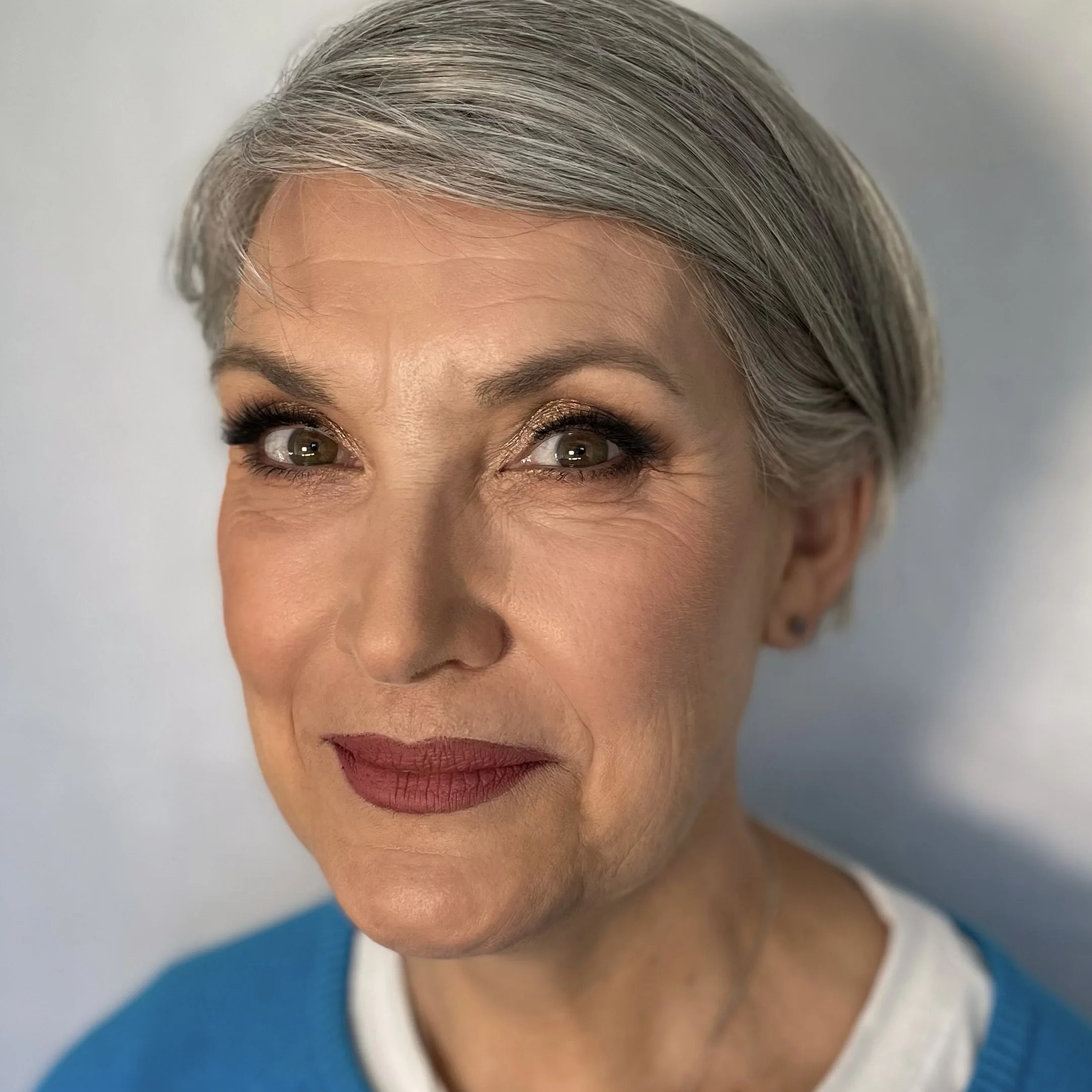 Softly smoked eye and a berry lip on grey hair, looking straight to camera