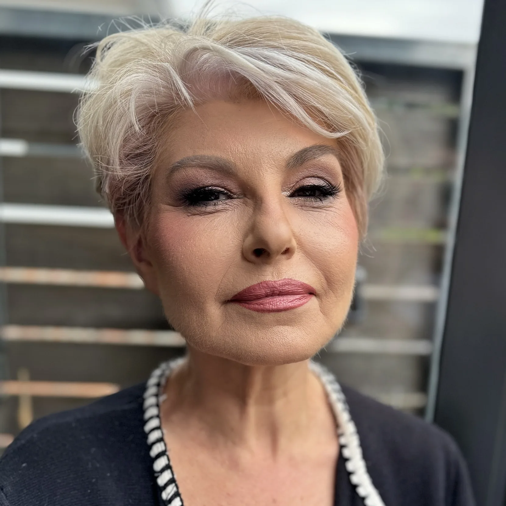 Defined smoky eye and a rose lip on platinum blonde hair, three-quarter view