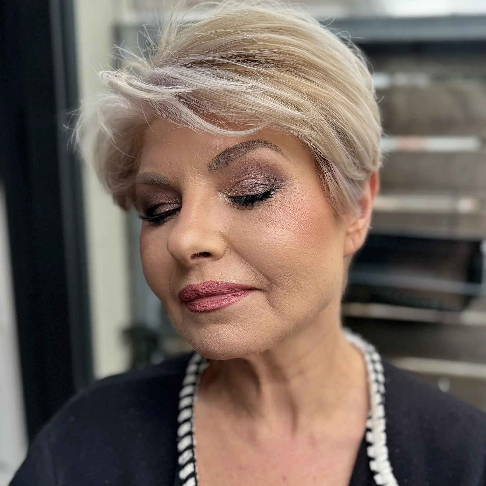 Taupe shimmer lid and a rose lip on a platinum pixie cut, eyes closed