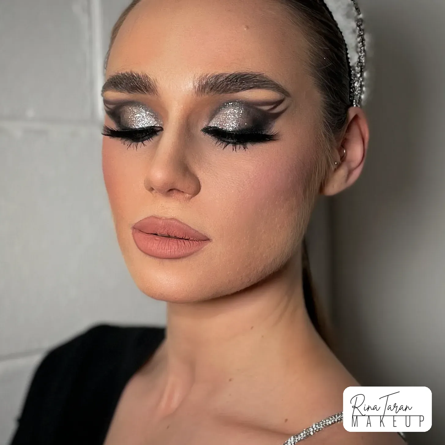 Silver glitter laid over a black smoky eye, with a graphic cut crease and full lashes