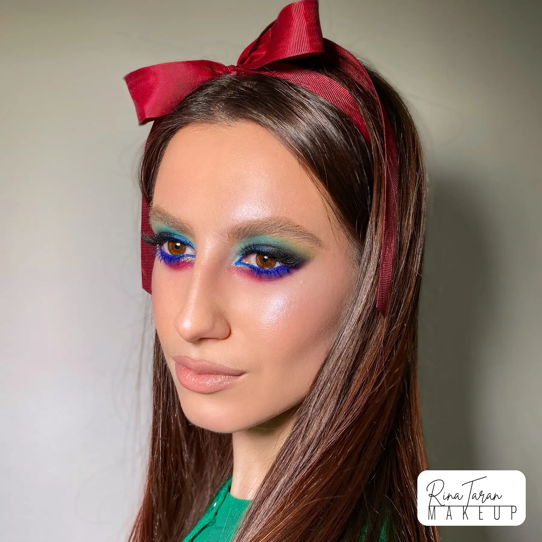 Bold race day makeup in emerald and sapphire, balanced back with a nude lip
