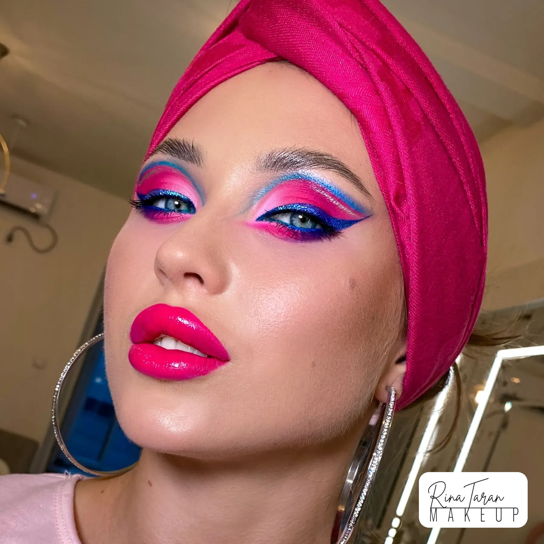 Bright carnival makeup with a pink and blue graphic eye and a hot pink lip