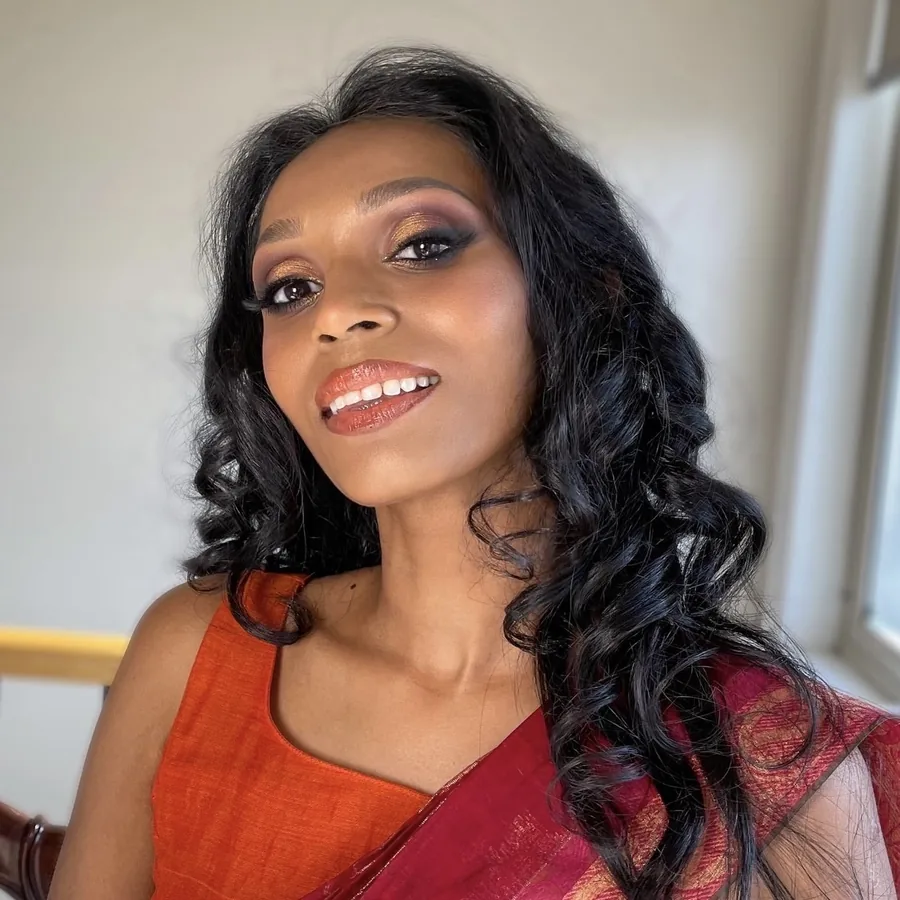 Laughing client in an orange and red sari, makeup still fresh late in the day